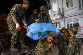 Lực lượng quân đội hỗ trợ bốc xếp, phân loại và đóng gói nông sản hỗ trợ các địa phương bị ảnh hưởng dịch COVID-19. (Ảnh: Nam Sương/TTXVN)