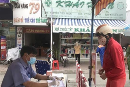 Lực lượng chức năng kiểm soát đối với người ra vào chợ Vĩnh Long, hạn chế tụ tập đông người. (Ảnh: Lê Thúy Hằng/TTXVN)