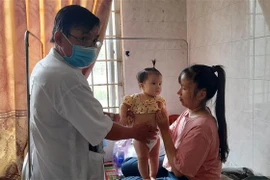 Chị Võ Thị Hồng Mỹ ở xã Bình Tường, huyện Tây Sơn cho con nhập viện sáng 20/3 sau khi xuất hiện các triệu chứng đau bụng, tiêu chảy. (Ảnh: Tường Quân/TTXVN)