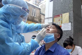 Nhân viên y tế lấy mẫu xét nghiệm COVID-19 cho người làm việc tại tòa nhà T&T Group. (Ảnh: Tuấn Đức/TTXVN)