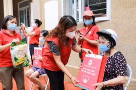 Phó Chủ tịch Hội Chữ thập Đỏ thành phố Hà Nội Đinh Thị Phức trao túi hàng gia đình tới người dân bị ảnh hưởng bởi dịch bệnh COVID-19 đang sống tại quận Thanh Xuân trong sáng 15/8. (Ảnh: Thanh Tùng/TTXVN)