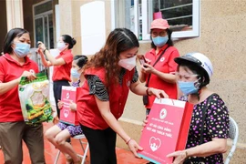 Phó Chủ tịch Hội Chữ thập Đỏ thành phố Hà Nội Đinh Thị Phức trao túi hàng gia đình tới người dân bị ảnh hưởng bởi dịch bệnh COVID-19 đang sống tại quận Thanh Xuân trong sáng 15/8. (Ảnh: Thanh Tùng/TTXVN)