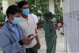 Cử tri khu phố Đa Ngư, phường Hòa Hiệp Nam, thị xã Đông Hòa, Phú Yên đọc thông tin ứng cử viên trước khi bầu cử. (Ảnh: Xuân Triệu/TTXVN)
