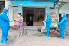Nhân viên y tế trạm y tế lưu động phường 25, quận Bình Thạnh phát túi thuốc cho F0 điều trị tại nhà. (Ảnh: Đinh Hằng/TTXVN)