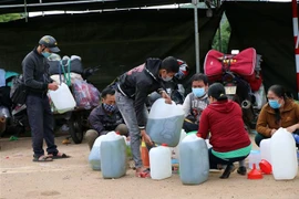 Người dân đi xe máy từ các tỉnh phía Nam về quê được lực lượng Cảnh sát giao thông Công an tỉnh Kon Tum hỗ trợ cơm, đồ ăn nhẹ, ước uống và xăng trước khi về quê ngày 27/7. (Ảnh: Cao Nguyên/TTXVN)