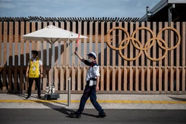 Nhân viên hướng dẫn cho các phương tiện tại lối vào làng vận động viên Olympic và Paralympic ở Tokyo, Nhật Bản, ngày 15/7/2021. (Ảnh: AFP/TTXVN)