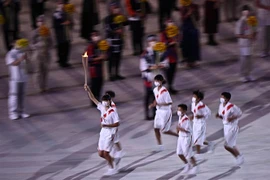 Các vận động viên rước đuốc Olympic tại lễ khai mạc Olympic Tokyo 2020 ở Tokyo, Nhật Bản, ngày 23/7. (Ảnh: AFP/TTXVN)
