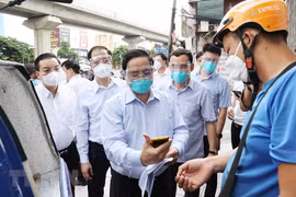 Thủ tướng Phạm Minh Chính kiểm tra giấy phép đi đường và khai báo y tế của một nhân viên giao hàng trên địa bàn quận Thanh Xuân chiều 31/8. (Ảnh: Dương Giang/TTXVN)