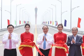 Thủ tướng Nguyễn Xuân Phúc và các đại biểu thực nghiện nghi thức cắt băng thông xe cầu Cửa Hội bắc qua Sông Lam. (Ảnh: Thống Nhất/TTXVN)