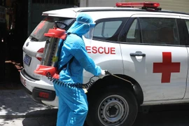 Nhân viên y tế phun khử khuẩn khi lấy mẫu xong. (Ảnh: Minh Quyết/TTXVN)