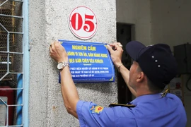 Lực lượng chức năng dán thông báo nghiêm cấm người lang thang xin ăn. (Nguồn: Báo Người Lao động)