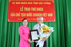 Phó Chủ tịch Ủy ban Nhân dân tỉnh Sóc Trăng Huỳnh Thị Diễm Ngọc trao thư khen của Chủ tịch nước cho cụ Trần Cang. (Ảnh: Trung Hiếu/TTXVN)