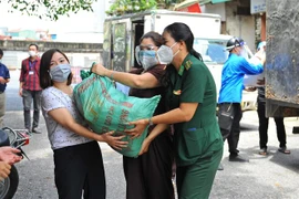 Lực lượng tình nguyện vận chuyển nhu yếu phẩm cho nhân dân phường Chương Dương và Phúc Tân. (Ảnh: Minh Đức/TTXVN)
