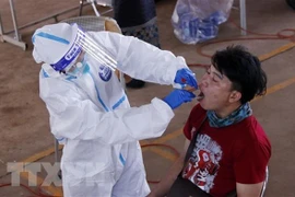 Bác sỹ lấy mẫu xét nghiệm cho một người dân ở Vientiane. (Ảnh: Phạm Kiên/TTXVN)