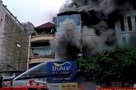 Cảnh sát nỗ lực chữa cháy cửa hàng sơn. (Ảnh: TTXVN phát)