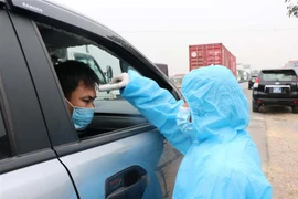 Kiểm tra thân nhiệt cho người vào địa bàn tỉnh Bắc Ninh tại chốt kiểm soát dịch bệnh xã Nghĩa Đạo, huyện Thuận Thành. (Ảnh: Thanh Thương/TTXVN)