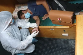 Ngư dân Đỗ Văn Hùng được cán bộ trên tàu kiểm ngư KN 462 sơ cứu ban đầu với các biện pháp phòng, chống dịch COVID-19. (Ảnh: TTXVN phát)