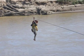 Người dân liều mình đu dây qua sông Pô Kô. (Ảnh: Khoa Chương/TTXVN)