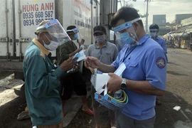 Trao tặng tấm chắn giọt bắn và khẩu trang cho người lao động tại cảng cá Quy Nhơn. (Ảnh: Nguyên Linh/TTXVN)