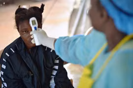 Nhân viên y tế kiểm tra thân nhiệt bệnh nhân nghi nhiễm virus Ebola tại Kenema, Guinea, ngày 16/8/2014. (Ảnh: AFP/TTXVN)