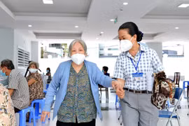 Các y bác sỹ Trung tâm Y tế quận 3, Thành phố Hồ Chí Minh, hỗ trợ, hướng dẫn người trên 65 tuổi, người mắc bệnh mãn tính, người thuộc hộ nghèo tiêm vaccine Moderna phòng COVID-19 đợt 5. (Ảnh: Thanh Vũ/TTXVN)