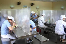Các công nhân được bố trí ngồi ăn giãn cách, có vách ngăn. (Ảnh: TTXVN)