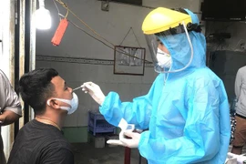 Người dân từ các tỉnh, thành phố có dịch COVID-19 được tiến hành test nhanh COVID-19 tại chốt kiểm soát trước khi vào tỉnh Vĩnh Long. (Ảnh: Lê Thúy Hằng/TTXVN)