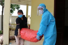 Đội ngũ tình nguyện viên chuyển thực phẩm từ các nhà tài trợ mang đến phát cho người dân tại xã Mão Điền. (Ảnh: Thanh Thương/TTXVN)