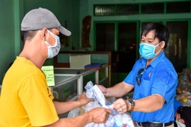 Trao quà cho công nhân ở trọ, người nghèo trong khu phong tỏa. (Ảnh: TTXVN phát)