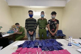 Hai đối tượng cùng tang vật tại cơ quan công an. (Ảnh: TTXVN phát)