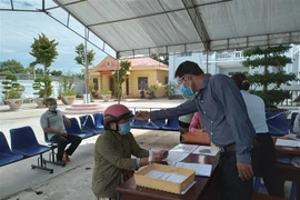 Đo thân nhiệt người bán vé số, người lao động tự do đến nhận hỗ trợ. (Ảnh minh họa. Nguồn: TTXVN)