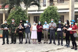 Lãnh đạo Trung đoàn Bộ binh 890 trao giấy chứng nhận hoàn thành cách ly tập trung cho các công dân Việt Nam trở về từ Anh. (Ảnh: Lê Thúy Hằng/TTXVN)