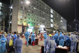 Trung tâm Kiểm soát bệnh tật Bình Dương phối hợp với Trung tâm Y tế thành phố Thủ Dầu Một tiến hành lấy mẫu xét nghiệm xuyên đêm. (Ảnh: Văn Hướng/TTXVN)