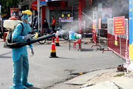 Phun thuốc tiêu độc, khử trùng tại khu vực dân cư có trường hợp dương tính với SARS-CoV-2. (Ảnh: Lê Ngọc Phước/TTXVN)