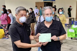Thứ trưởng Bộ Y tế Nguyễn Trường Sơn (trái) trao giấy ra viện cho ông Piers Edmund Astley Birtwistle, 63 tuổi, người Anh (trú tại thành phố Thủ Đức, Thành phố Hồ Chí Minh) - một trong 17 bệnh nhân COVID-19 được xuất viện. (Ảnh: Hồng Giang/TTXVN)
