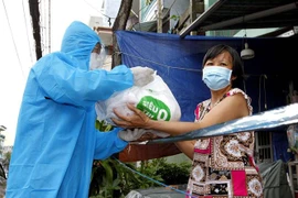 Tình nguyện viên chương trình 'Siêu thị 0 đồng di động' trao quà cho người lao động nghèo trên đường Hưng Phú, quận 8, Thành phố Hồ Chí Minh. (Ảnh: Thanh Vũ/TTXVN)