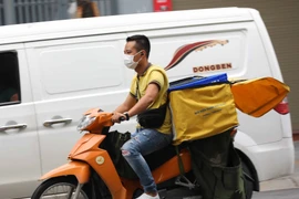 Nhiều nhân viên giao hàng đã không tuân thủ việc đội mũ bảo hiểm. (Ảnh: Thanh Tùng/TTXVN)