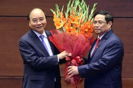 Thủ tướng Phạm Minh Chính tặng hoa Chủ tịch nước Nguyễn Xuân Phúc, Thủ tướng Chính phủ nhiệm kỳ 2016-2021. (Ảnh: Thống Nhất/TTXVN)