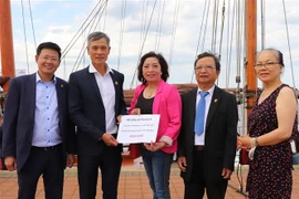 Đại sứ Nguyễn Minh Vũ (thứ 2 từ trái sang) tiếp nhận số tiền quyên góp của cộng đồng người Việt ở thành phố Rostock và vùng phụ cận. (Ảnh: Mạnh Hùng/TTXVN)