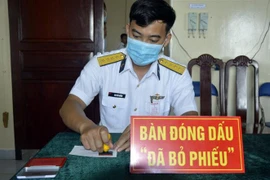 Thành viên Tổ Bầu cử sớm đóng dấu đã bỏ phiếu cho cử tri tại Nhà giàn DK1/17. (Ảnh: TTXVN phát)