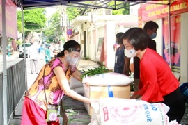 Phó Chủ tịch Liên hiệp các tổ chức hữu nghị thành phố Hà Nội Trần Thị Phương (phải) trao quà hỗ trợ cho người dân phường Phúc Xá. (Ảnh: Nguyễn Cúc/TTXVN)