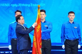 Ông Vương Đình Huệ - Ủy viên Bộ Chính trị, Bí thư Thành uỷ Hà Nội gắn Huân chương Lao động hạng Nhất lên cờ truyền thống của Thành đoàn Hà Nội. (Ảnh: Minh Đức/TTXVN)
