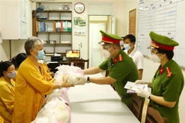 Cán bộ, chiến sỹ Công an phường Mai Dịch (quận Cầu Giấy, Hà Nội) trao quà hỗ trợ cho người nhà bệnh nhân có hoàn cảnh khó khăn đang điều trị tại Khoa điều trị tích cực và chống độc, bệnh viện 19/8 Bộ Công an. (Ảnh: Phạm Kiên/TTXVN)