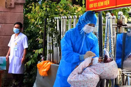 Người dân chờ được xét nghiệm nhanh trước khi vào khám, điều trị tại bệnh viện. (Ảnh: Công Tường/TTXVN)