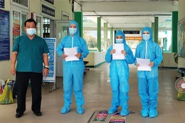 Bác sỹ Lê Thành Phúc trao giấy chứng nhận khỏi bệnh cho BN3396, BN3397, BN3398. (Ảnh: Văn Dũng/TTXVN)