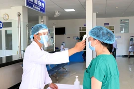 Đo thân nhiệt cho các trường hợp tiêm vaccine phòng COVID-19. (Ảnh: Quang Thái/TTXVN)