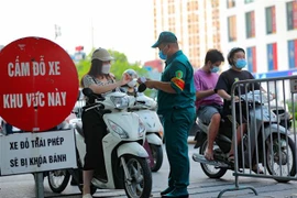 Các chốt kiểm soát của Ban chỉ đạo phòng chống dịch phường Vĩnh Tuy kiểm tra giấy tờ, thông tin của người ra, vào trên địa bàn. (Ảnh: Thanh Tùng/TTXVN)