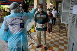 Kiểm tra thân nhiệt phòng lây nhiễm COVID-19 tại Campuchia. (Ảnh: AFP/TTXVN)