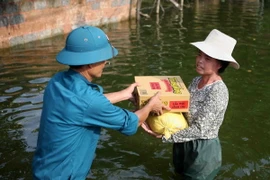Quà hỗ trợ của Hội Chữ thập Đỏ thành phố Hà Nội được giao tận tay người dân trong vùng ngập. (Ảnh: Thanh Tùng/TTXVN)