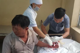 Nhân viên Bệnh viện Đa khoa Bạc Liêu khâu vét thương cho nạn nhân bị thương. (Ảnh: Huỳnh Sử/TTXVN)